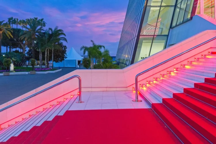 Illuminated red carpet stairs at the Palais des Festivals in Cannes at dusk — VIP private chauffeur access